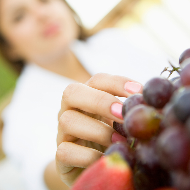 Photo of woman reaching for grapes.