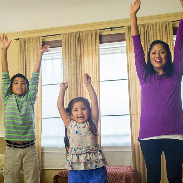 Photo of Champion mom with children exercising in living room.